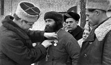Командир 5-й партизанской бригады Герой Советского Союза Константин Карицкий 
вручает медаль «Партизану Отечественной войны II степени» священнику Феодору Пузанову. Ленинградская обл., 1944. <br>Ист.: forum.vgd.ru